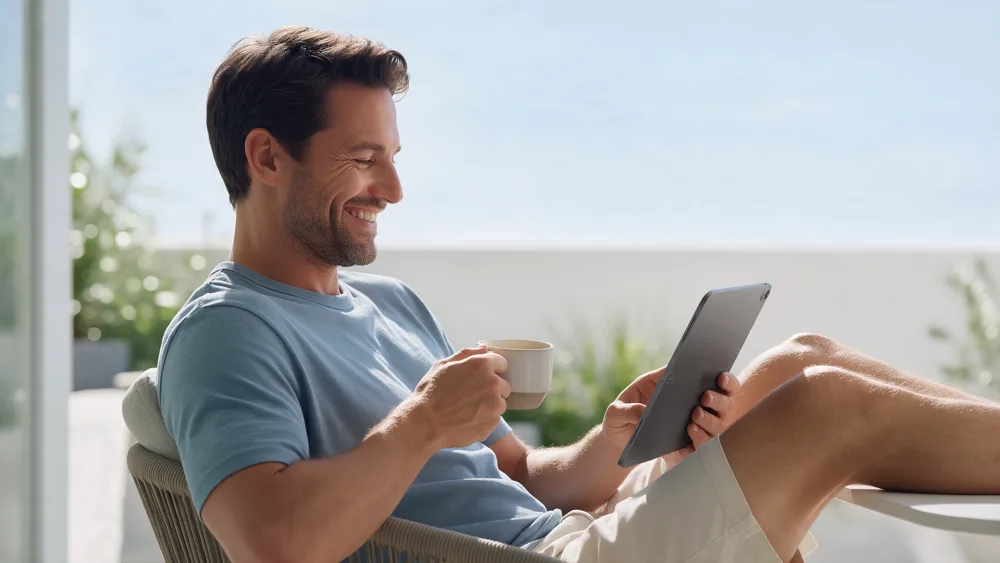 A smiling man with coffee looking at his iPad